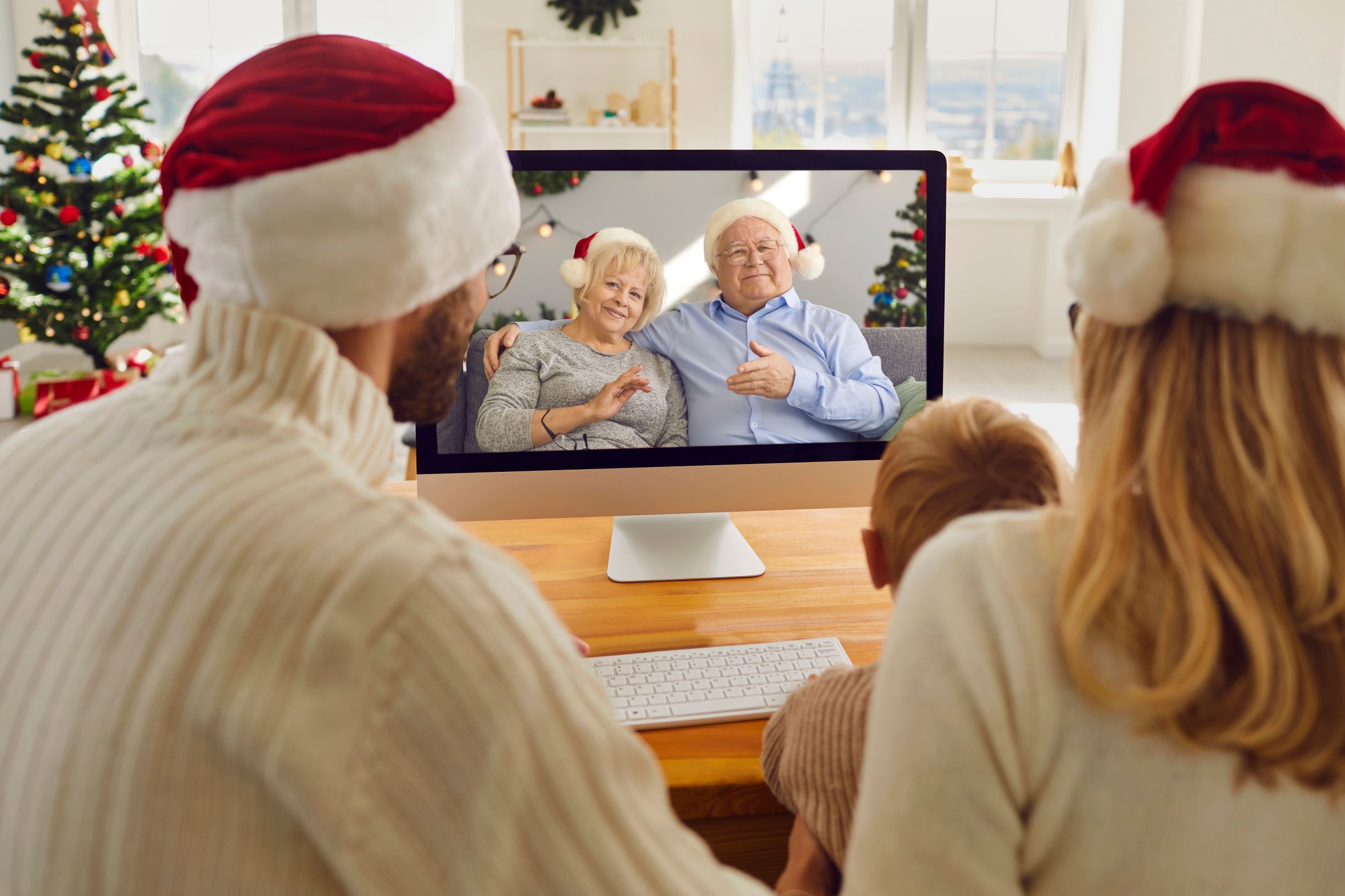 Family wearing Christmas talking to grand parents via video call.