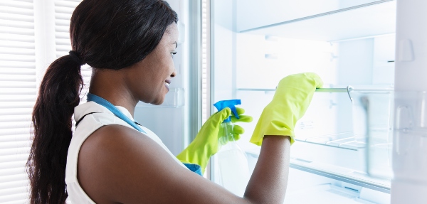 Woman cleaning the inside of a fridge